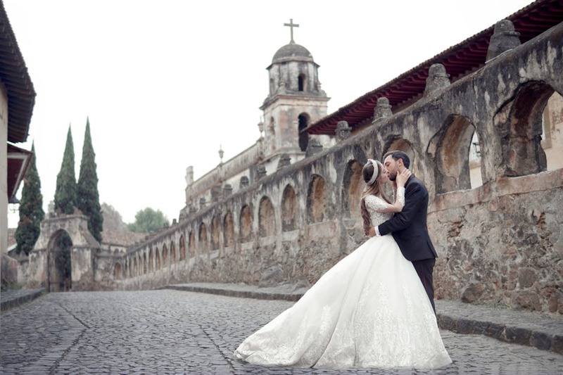 Bride and groom embracing on cobblestone street with historic church backdrop in Pátzcuaro, Mexico.