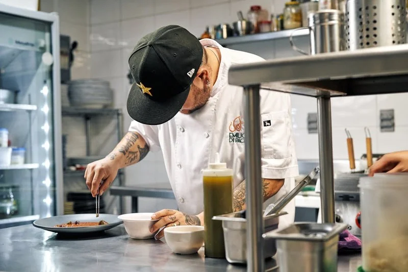 Chef preparando prato com ingredientes frescos e locais em cozinha sustentável