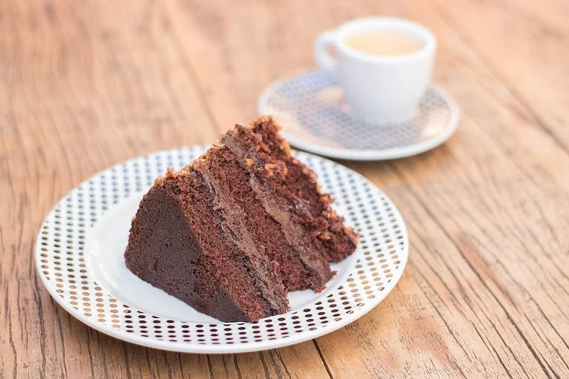 Pessoa apreciando café especial e bolo de chocolate