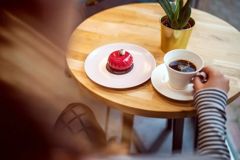 Pessoa desfrutando de café e sobremesa harmonizados em um café aconchegante