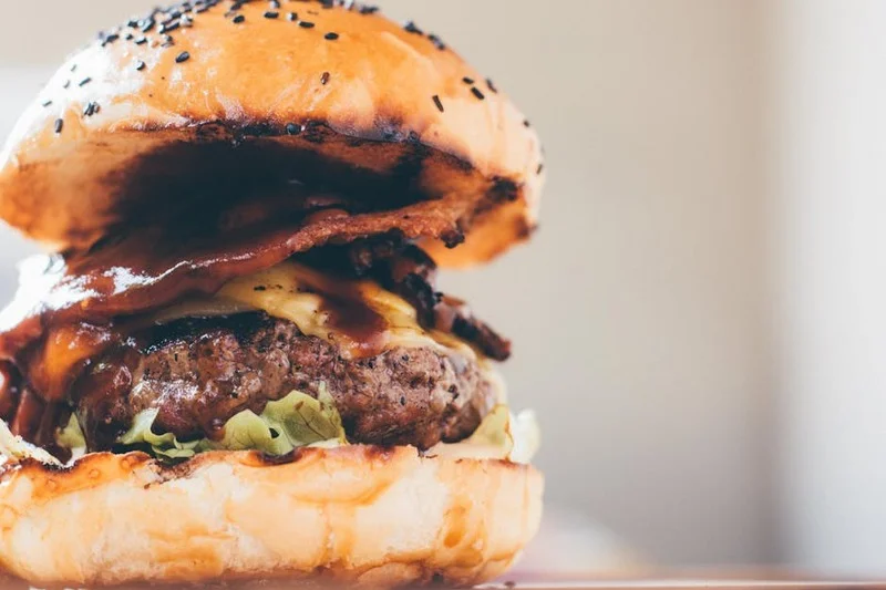 Hambúrguer gourmet com queijo derretido, bacon crocante e vegetais frescos em pão brioche