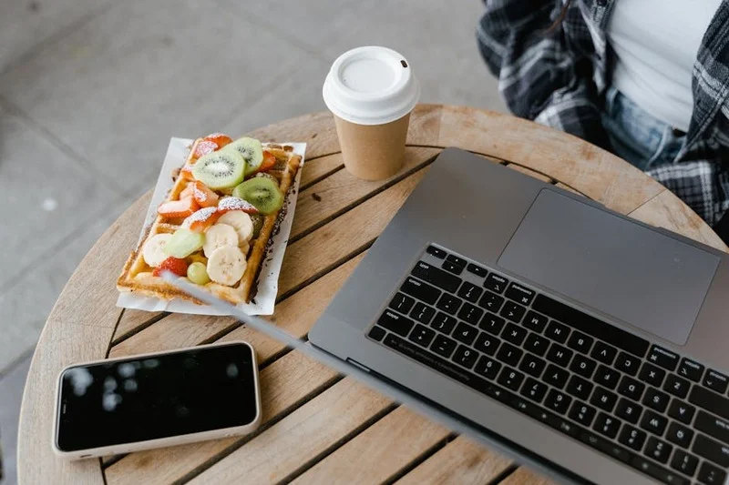 Mesa com waffle e café, ao lado de tigela com comida para cachorro em pátio