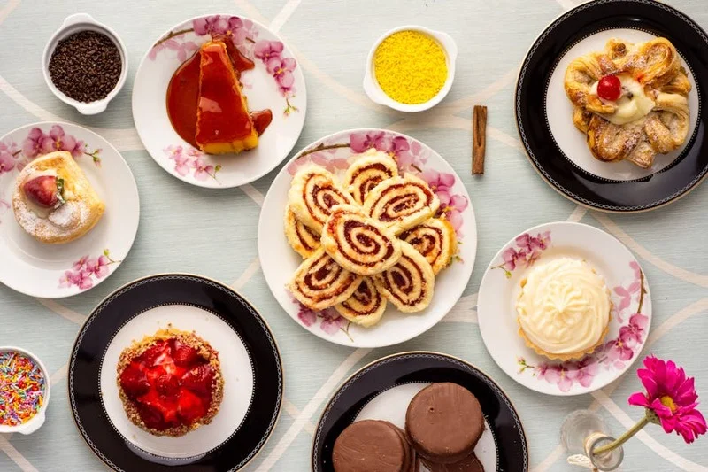 Variedade de sobremesas deliciosas em uma mesa, incluindo bolo de chocolate, torta de frutas e cheesecake