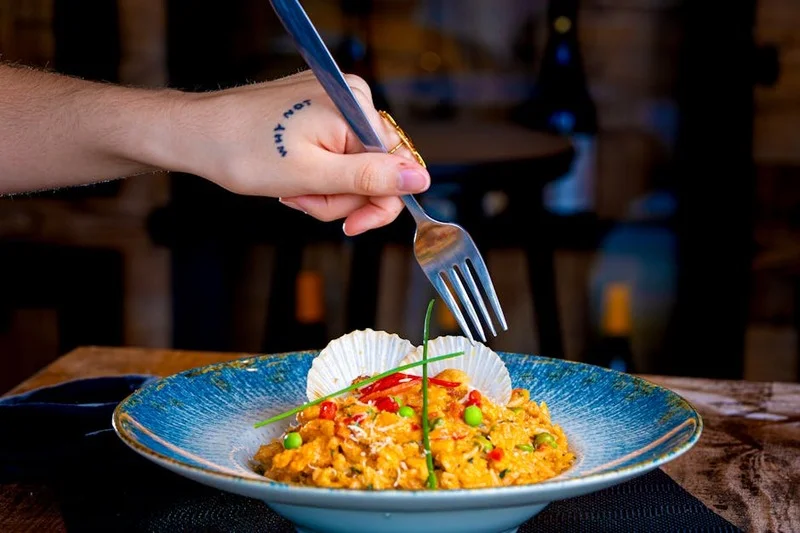 Risoto de frutos do mar gourmet servido em mesa ao lado de cachorro bem-comportado na coleira