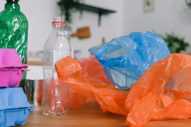 Pessoa embalando uma pequena bolsa com petiscos para cachorro, uma garrafa de água e sacos de lixo para um passeio